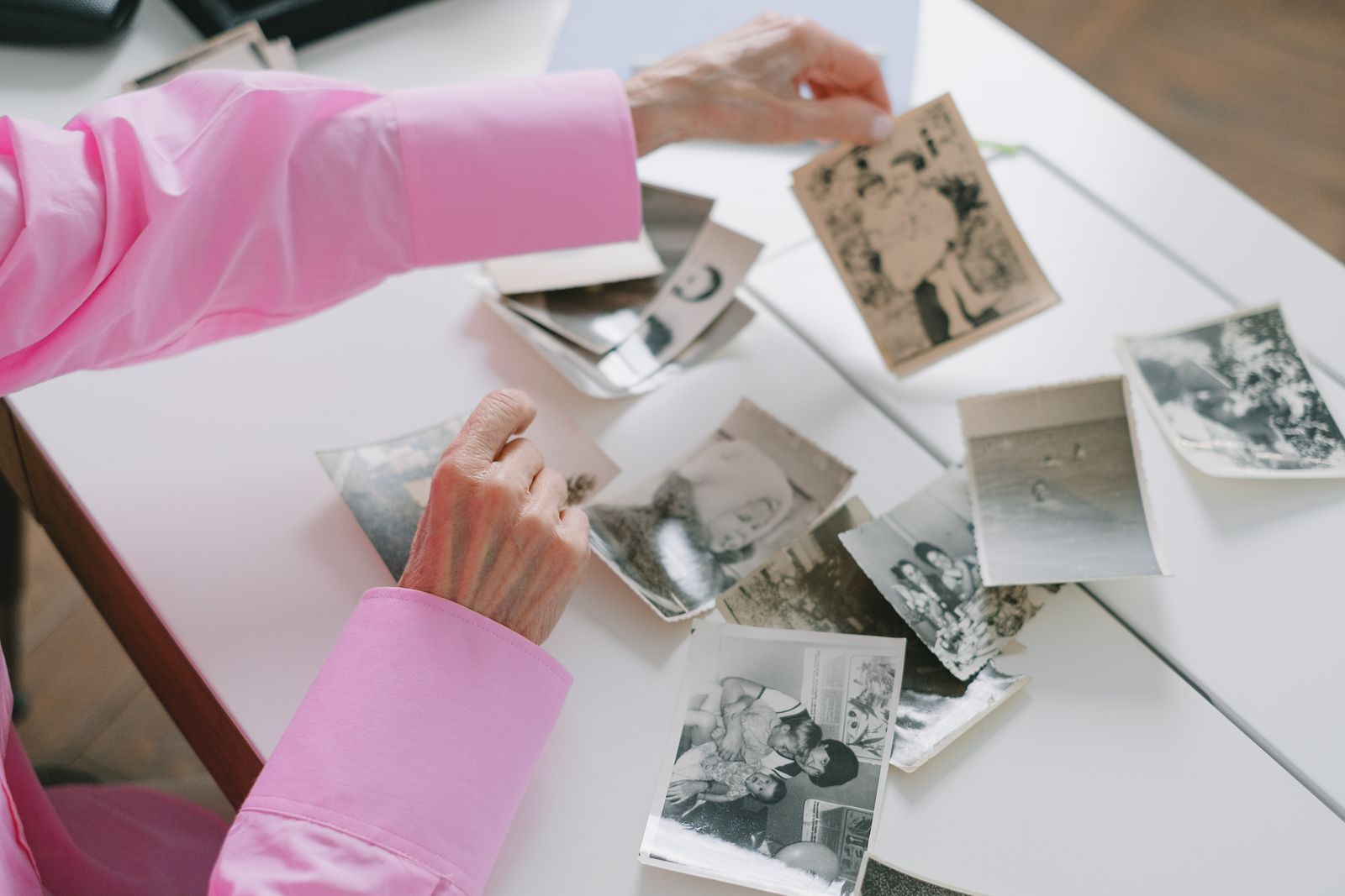 Older woman sorting through black-and-white family photographs at a table