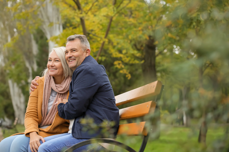 A happy couple sitting together on a park bench